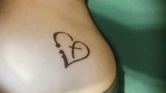 Minimalistic cross and heart tattoo located on the